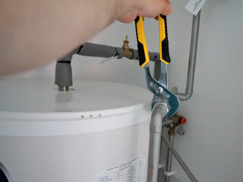 Technicien réglant un raccord de chauffe-eau à la pince