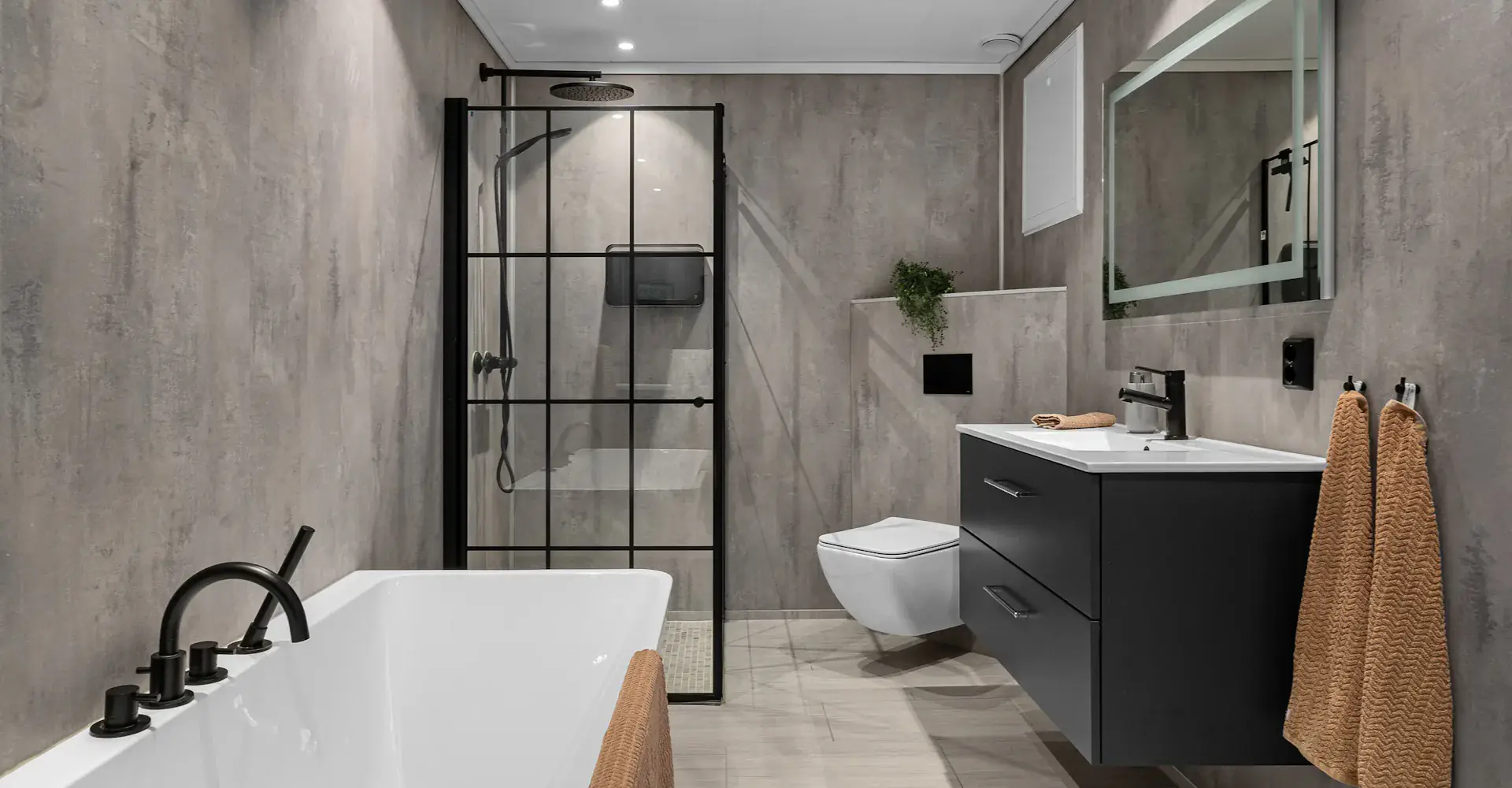 Salle de bains contemporaine : baignoire, douche à verrière noire, meuble suspendu et murs effet béton