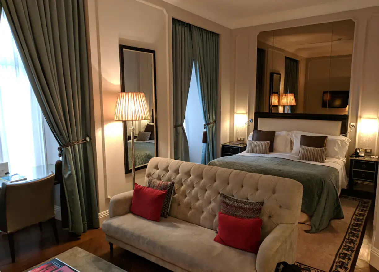 Chambre de l'hôtel : canapé capitonné, coussins framboise et lit double