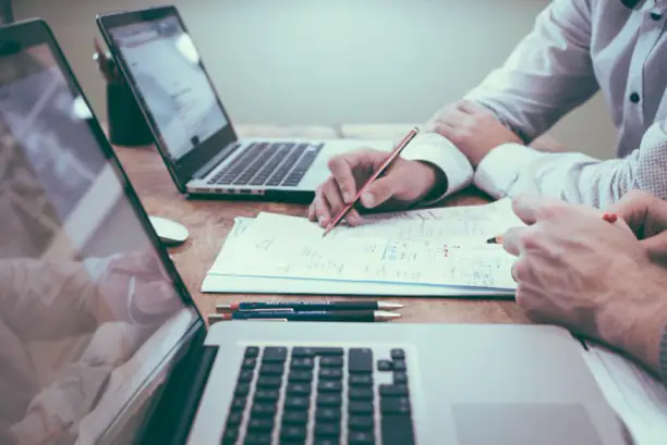 Deux personnes travaillant sur des documents et un ordinateur